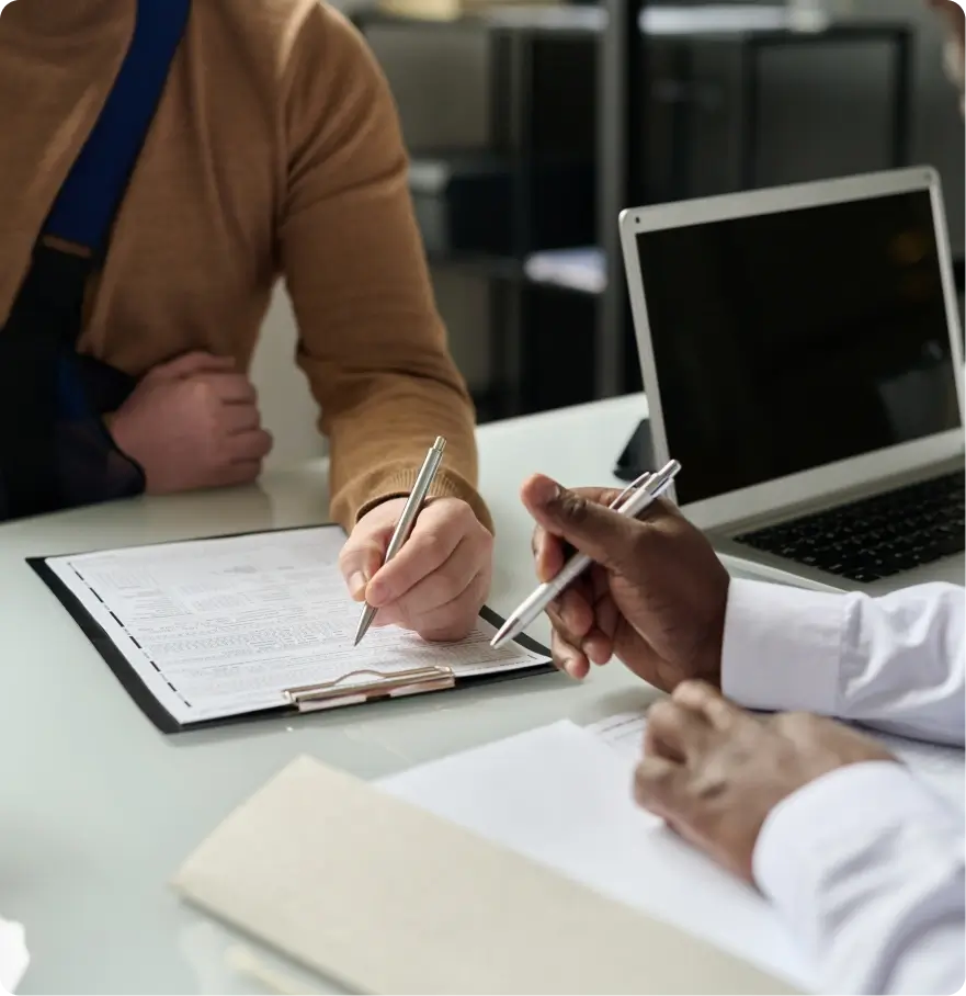 Person signing paperwork with an assistant.