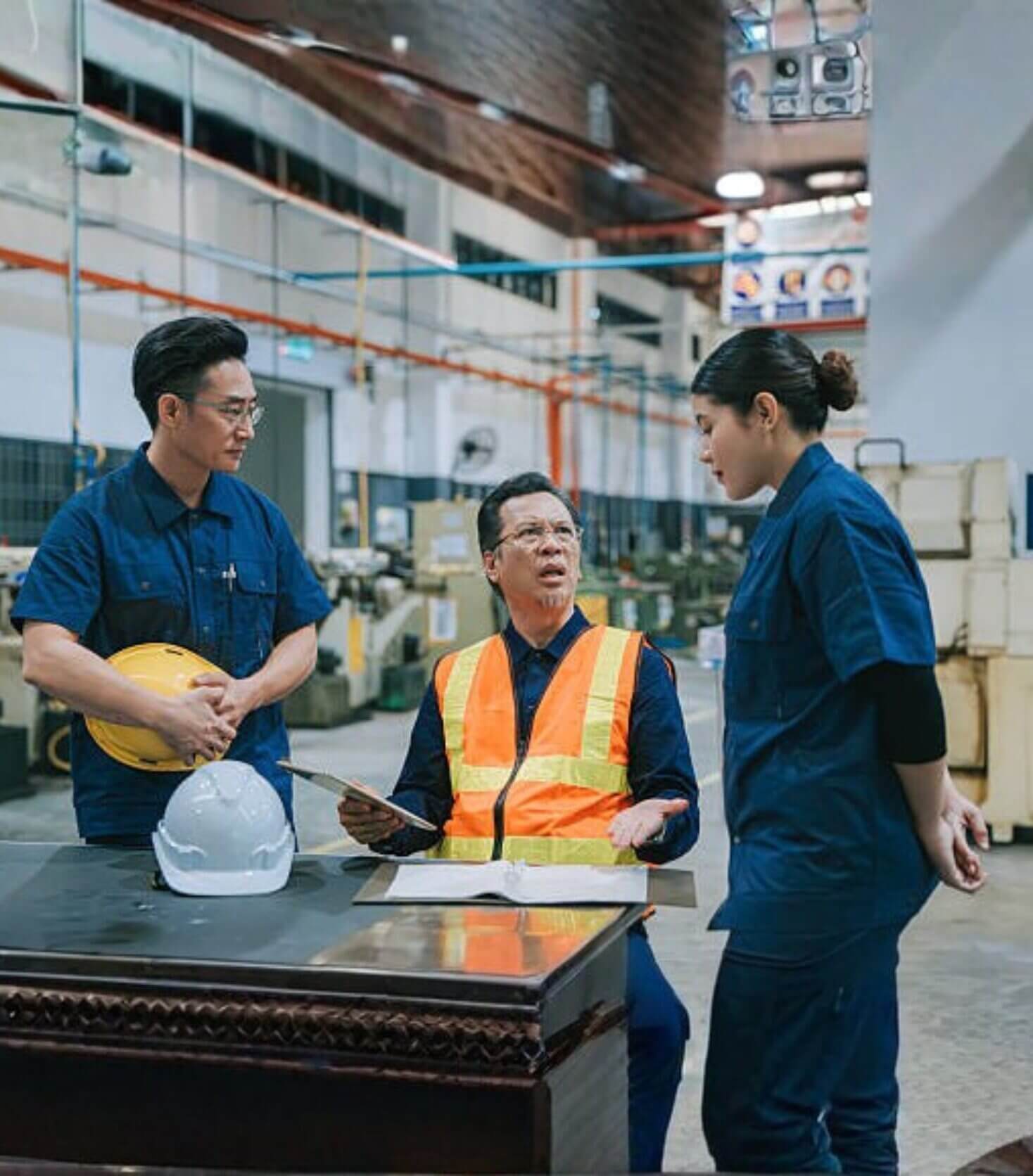 Factory workers discussing plans at a table.